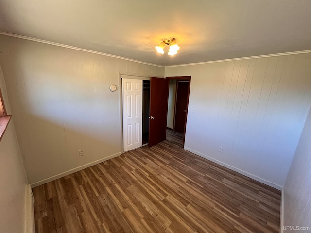 unfurnished room featuring wooden walls, dark hardwood / wood-style floors, and crown molding