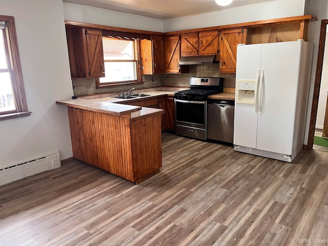 kitchen featuring kitchen peninsula, stainless steel appliances, hardwood / wood-style floors, and sink