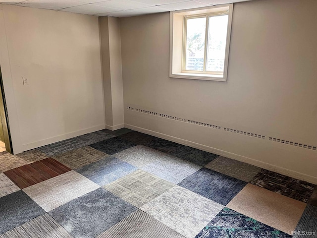 carpeted empty room featuring a drop ceiling