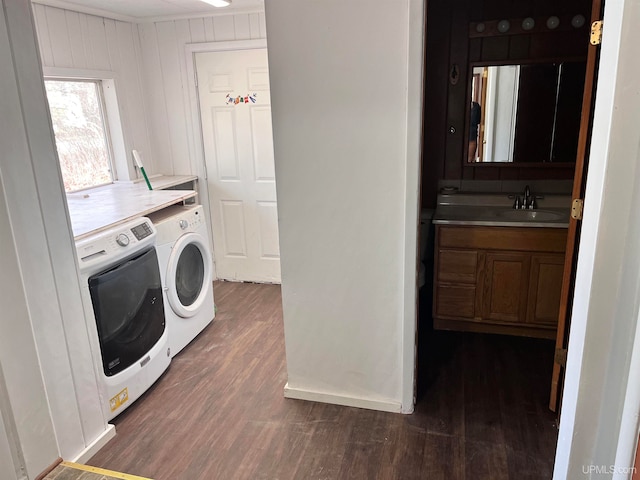 laundry area with washing machine and dryer, dark hardwood / wood-style floors, wooden walls, and sink