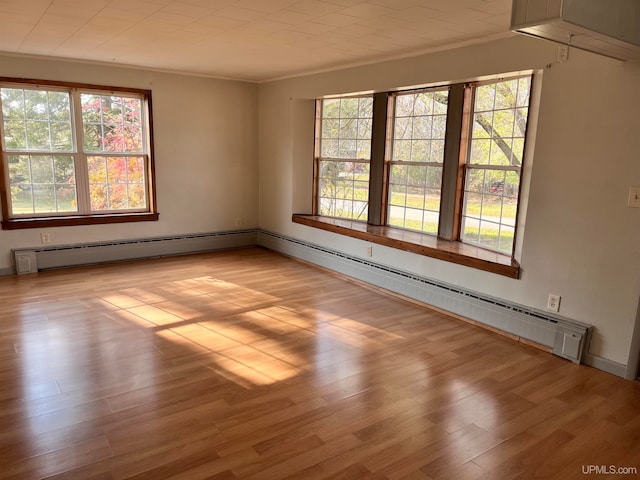 empty room with a baseboard radiator, light hardwood / wood-style flooring, and crown molding