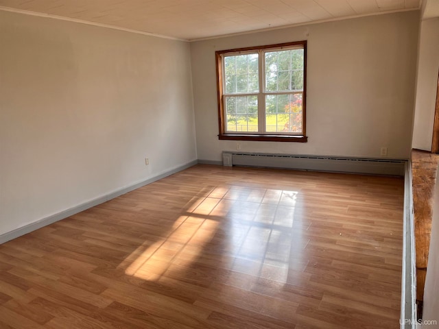 empty room featuring light wood-type flooring, baseboard heating, and crown molding