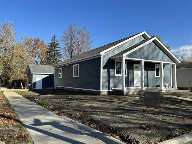 bungalow-style house featuring covered porch and an outbuilding