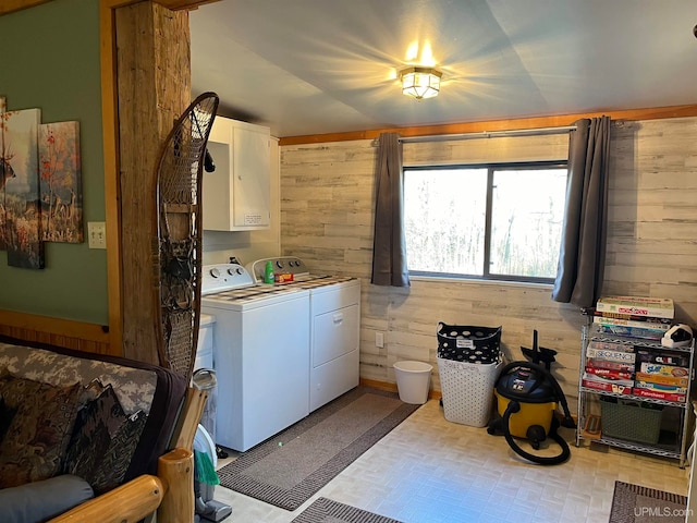 washroom with washer and clothes dryer, cabinets, and wooden walls