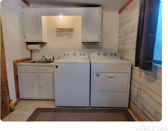 laundry area with cabinets, wood walls, sink, and washer and dryer