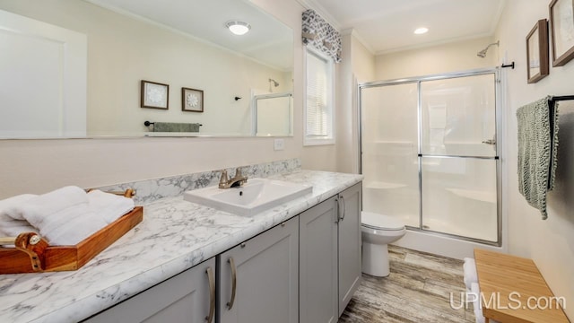 bathroom featuring wood-type flooring, vanity, an enclosed shower, and ornamental molding