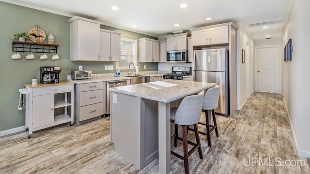 kitchen with a kitchen island, appliances with stainless steel finishes, sink, light hardwood / wood-style floors, and white cabinets