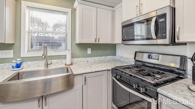 kitchen with white cabinets, stainless steel appliances, sink, and light stone counters