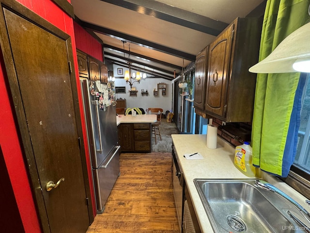 kitchen featuring vaulted ceiling with beams, stainless steel refrigerator, dark hardwood / wood-style floors, hanging light fixtures, and sink