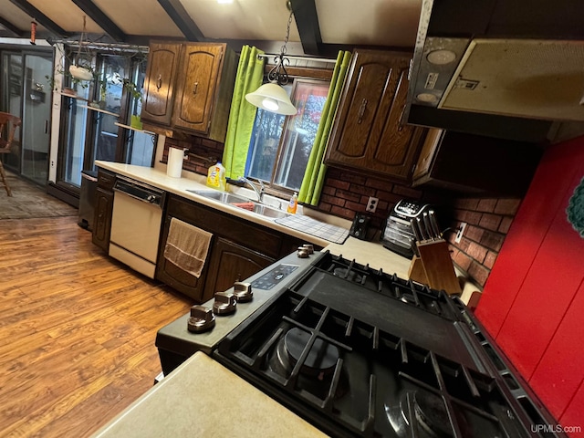 kitchen with sink, white dishwasher, decorative light fixtures, vaulted ceiling with beams, and light hardwood / wood-style flooring