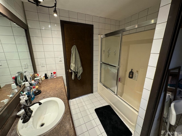 bathroom with tile walls, shower / bath combination with glass door, tile patterned floors, and vanity