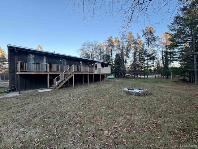 rear view of house with a yard, an outdoor fire pit, and a wooden deck