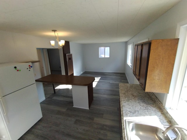 kitchen with an inviting chandelier, sink, dark hardwood / wood-style floors, white fridge, and pendant lighting