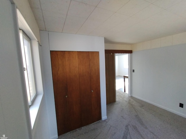 unfurnished bedroom with light colored carpet and a closet