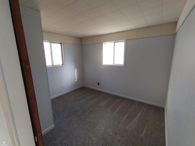 empty room featuring dark colored carpet and plenty of natural light