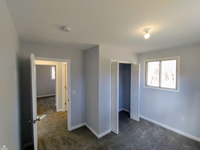 unfurnished bedroom featuring dark colored carpet and a closet