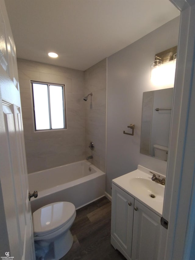 full bathroom with vanity, hardwood / wood-style flooring, tiled shower / bath, and toilet