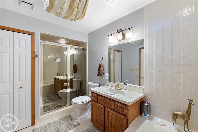 bathroom with vanity, a shower with door, tile patterned floors, and toilet