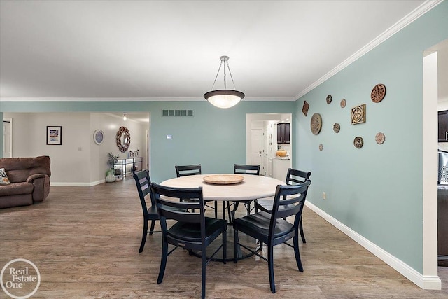 dining space featuring hardwood / wood-style flooring and crown molding