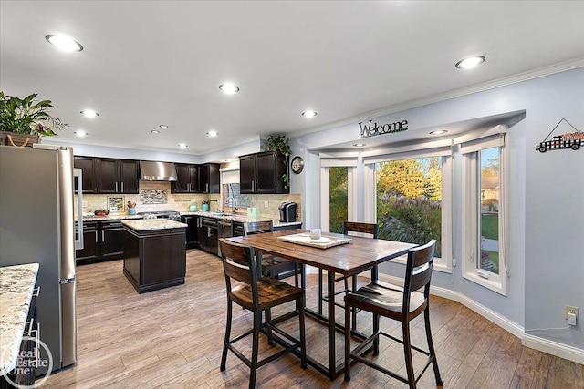 dining room featuring light wood-type flooring, sink, and crown molding