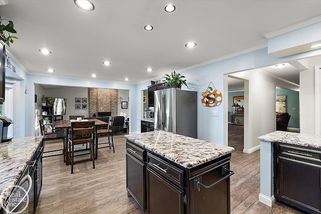 kitchen with a fireplace, light hardwood / wood-style flooring, a kitchen island, and stainless steel refrigerator