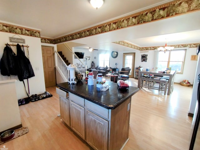 kitchen featuring ceiling fan with notable chandelier, light wood-type flooring, and a kitchen island