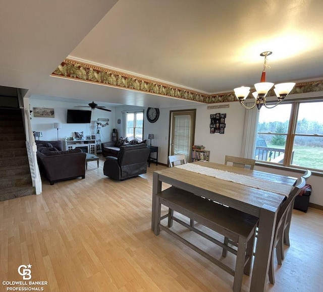 dining space with a wealth of natural light, ceiling fan with notable chandelier, and light hardwood / wood-style flooring