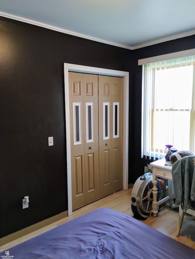 bedroom featuring a closet, light wood-type flooring, and multiple windows