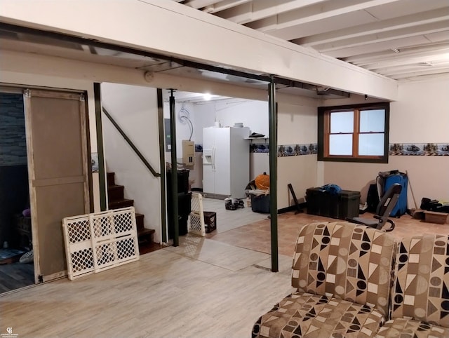 basement with hardwood / wood-style floors and white fridge with ice dispenser