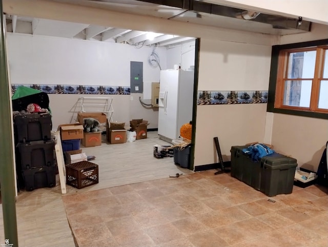 basement featuring white fridge with ice dispenser and electric panel