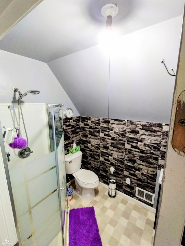 bathroom featuring a shower with door, toilet, and lofted ceiling