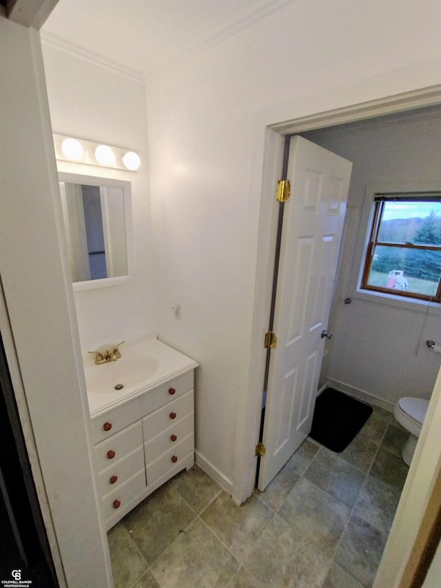 bathroom featuring toilet, vanity, and ornamental molding