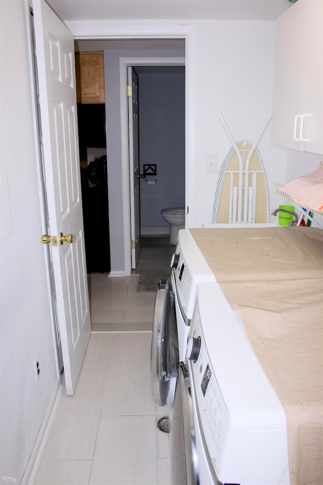 clothes washing area featuring cabinets and washing machine and dryer