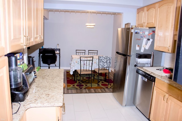 kitchen with appliances with stainless steel finishes, light brown cabinets, and pendant lighting