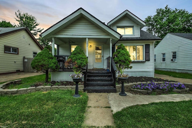 bungalow-style home with a lawn, cooling unit, and covered porch