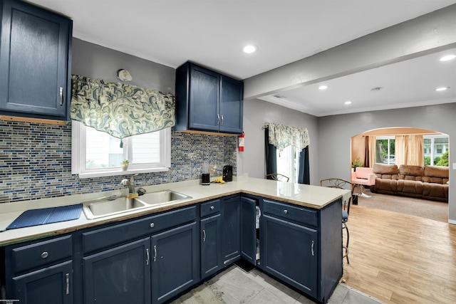 kitchen featuring sink, tasteful backsplash, light hardwood / wood-style flooring, blue cabinets, and kitchen peninsula