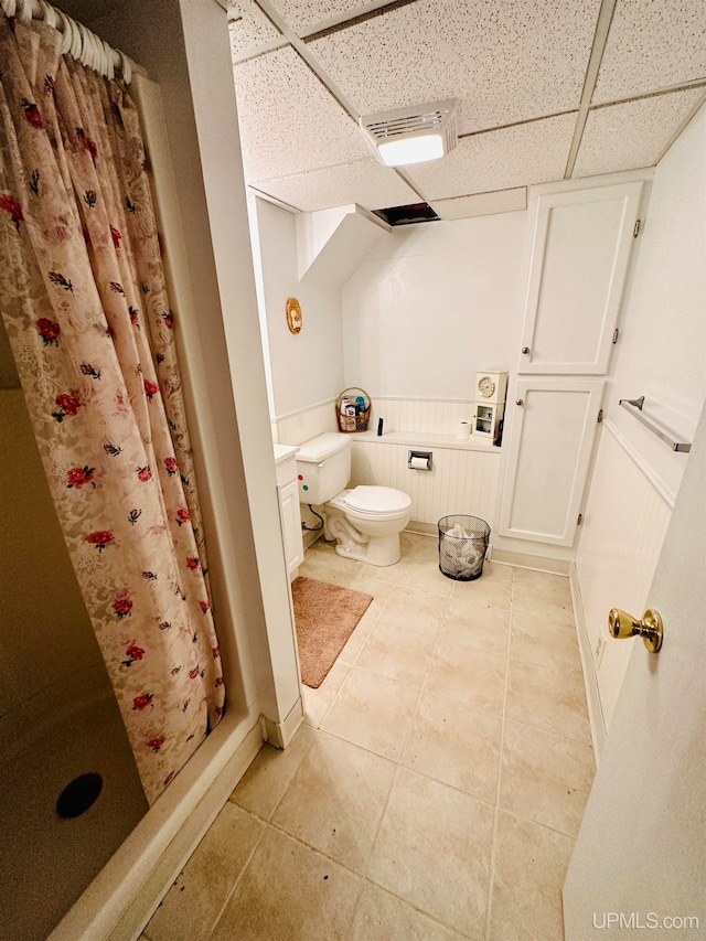 bathroom with a shower with curtain, tile patterned flooring, a paneled ceiling, and toilet