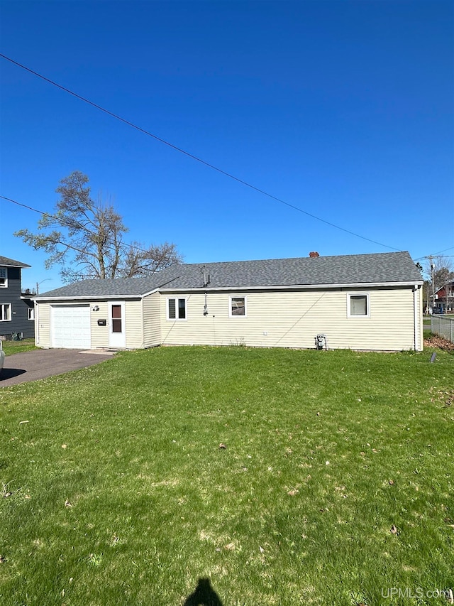 back of house featuring a garage and a lawn