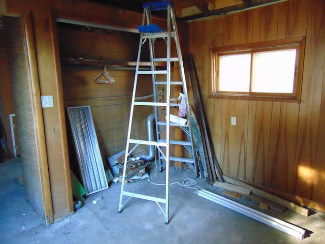 misc room with concrete flooring and wooden walls