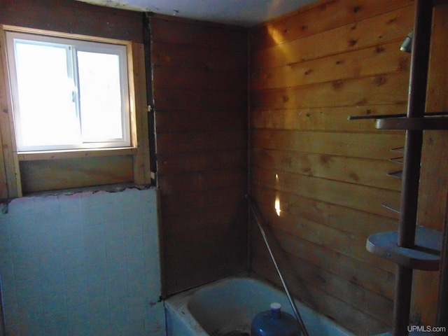 bathroom featuring a bathtub and wood walls