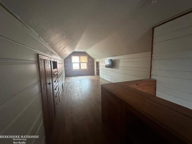 bonus room featuring wooden walls, hardwood / wood-style floors, and lofted ceiling