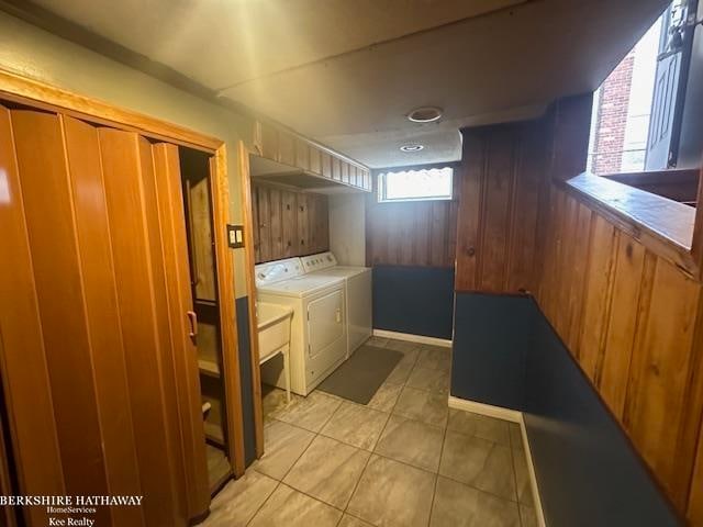 laundry room with wooden walls, light tile patterned floors, and independent washer and dryer