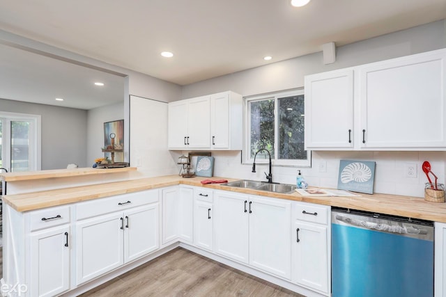 kitchen with butcher block counters, white cabinetry, light hardwood / wood-style floors, stainless steel dishwasher, and kitchen peninsula