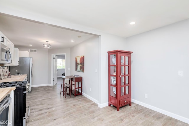 kitchen featuring light hardwood / wood-style flooring, appliances with stainless steel finishes, and white cabinets