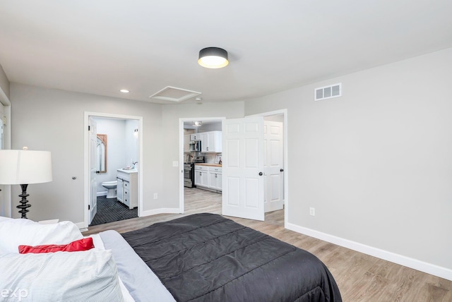 bedroom with light hardwood / wood-style floors and ensuite bathroom