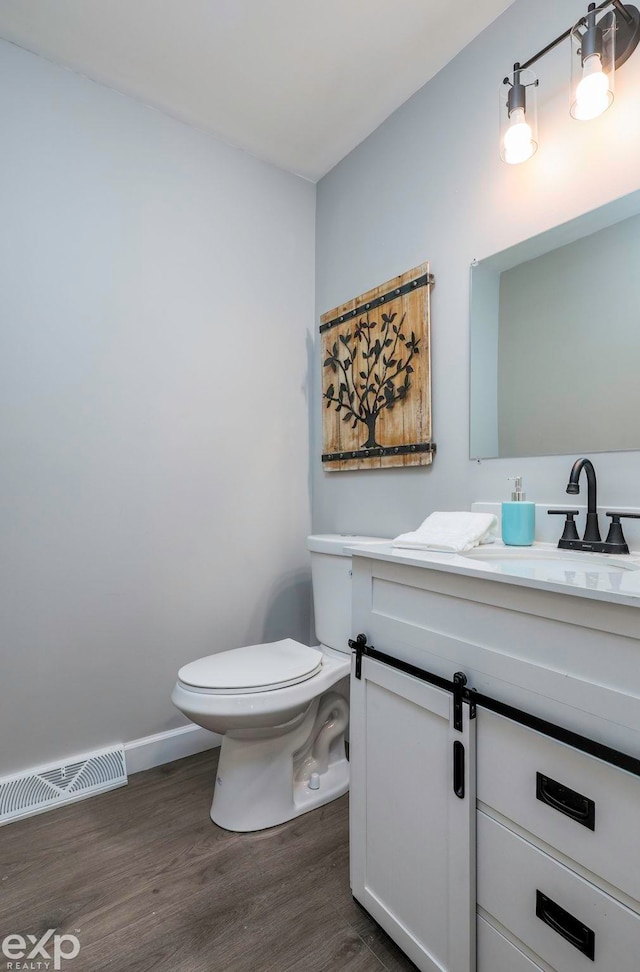 bathroom with toilet, vanity, and wood-type flooring