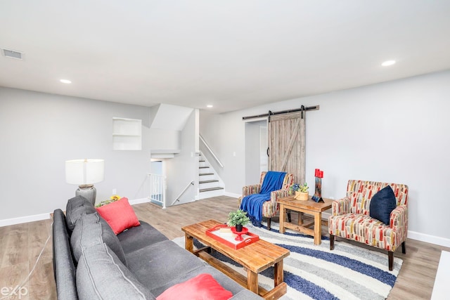 living room featuring a barn door and light hardwood / wood-style flooring