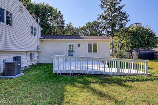 rear view of house with a deck, a storage unit, and a lawn