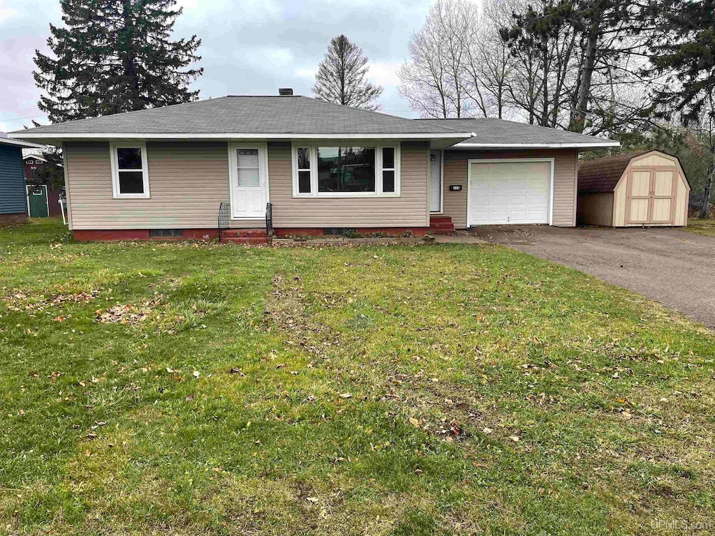 single story home featuring a garage, a shed, and a front lawn