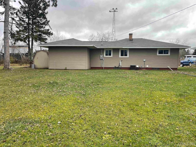 rear view of property with a storage unit and a yard